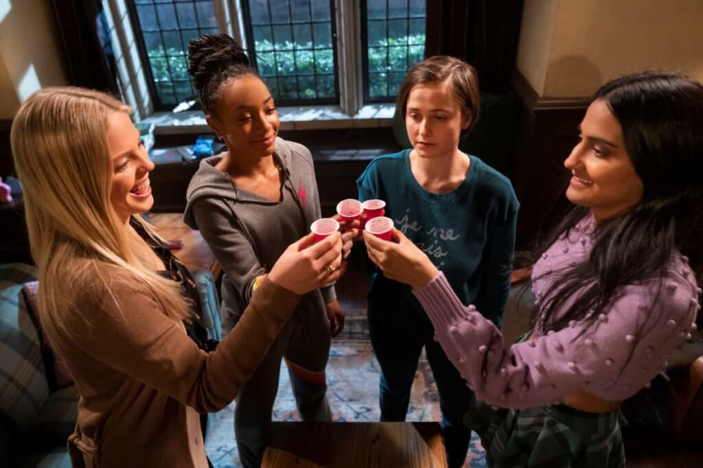 Reneé Rapp, Alyah Chanelle Scott, Pauline Chalamet e Amrit Kaur brindando em copos de papel e cena de The Sex Lives of College Girls
